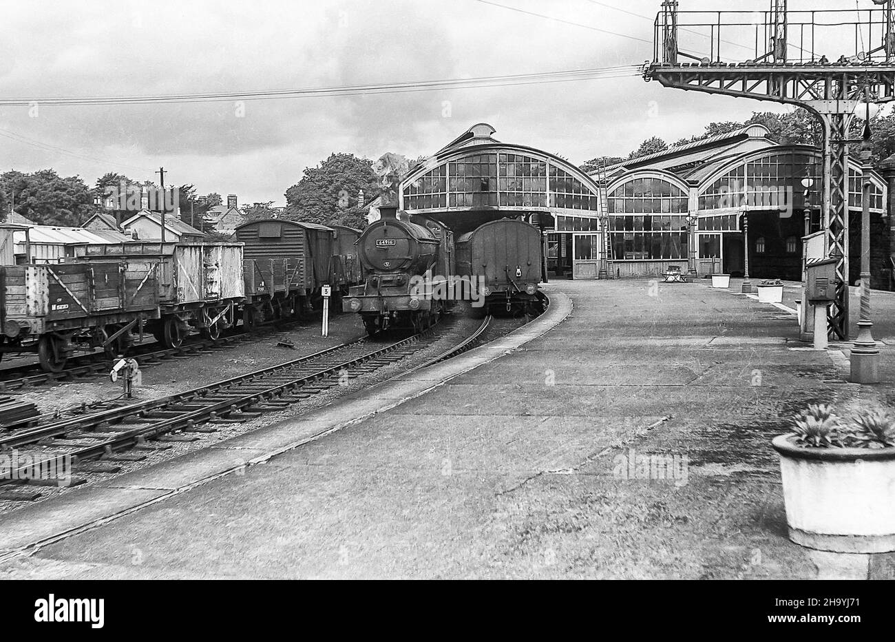 L'immagine da un negativo monocromatico scansionato è della stazione ferroviaria di Alnwick nel Northumberland come era nel luglio 1957 con il treno a vapore 64916 in posizione inattiva Foto Stock