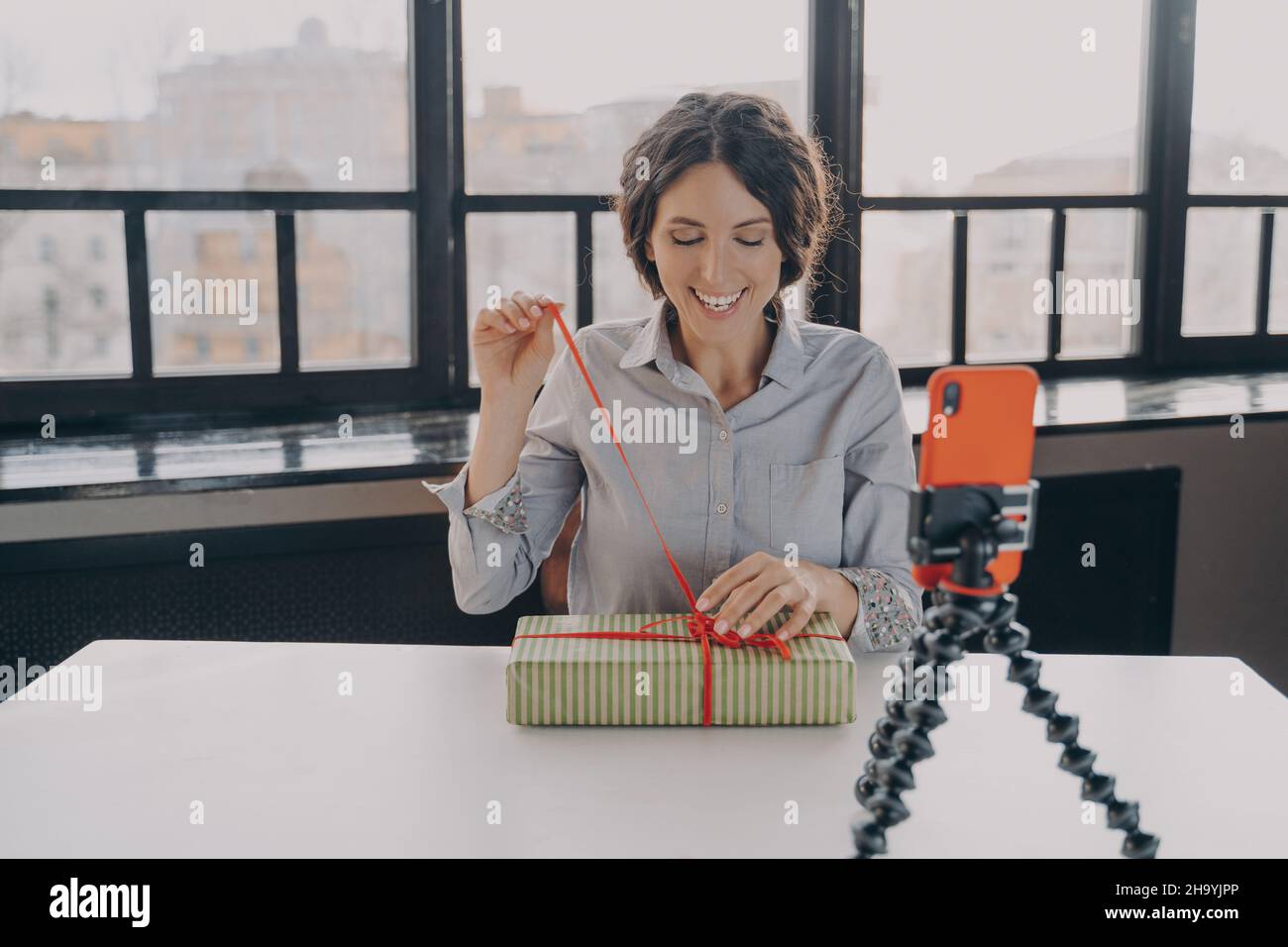 Eccitata donna ispanica blogger apertura scatola regalo registrazione video su Natale presente per il suo blog Foto Stock