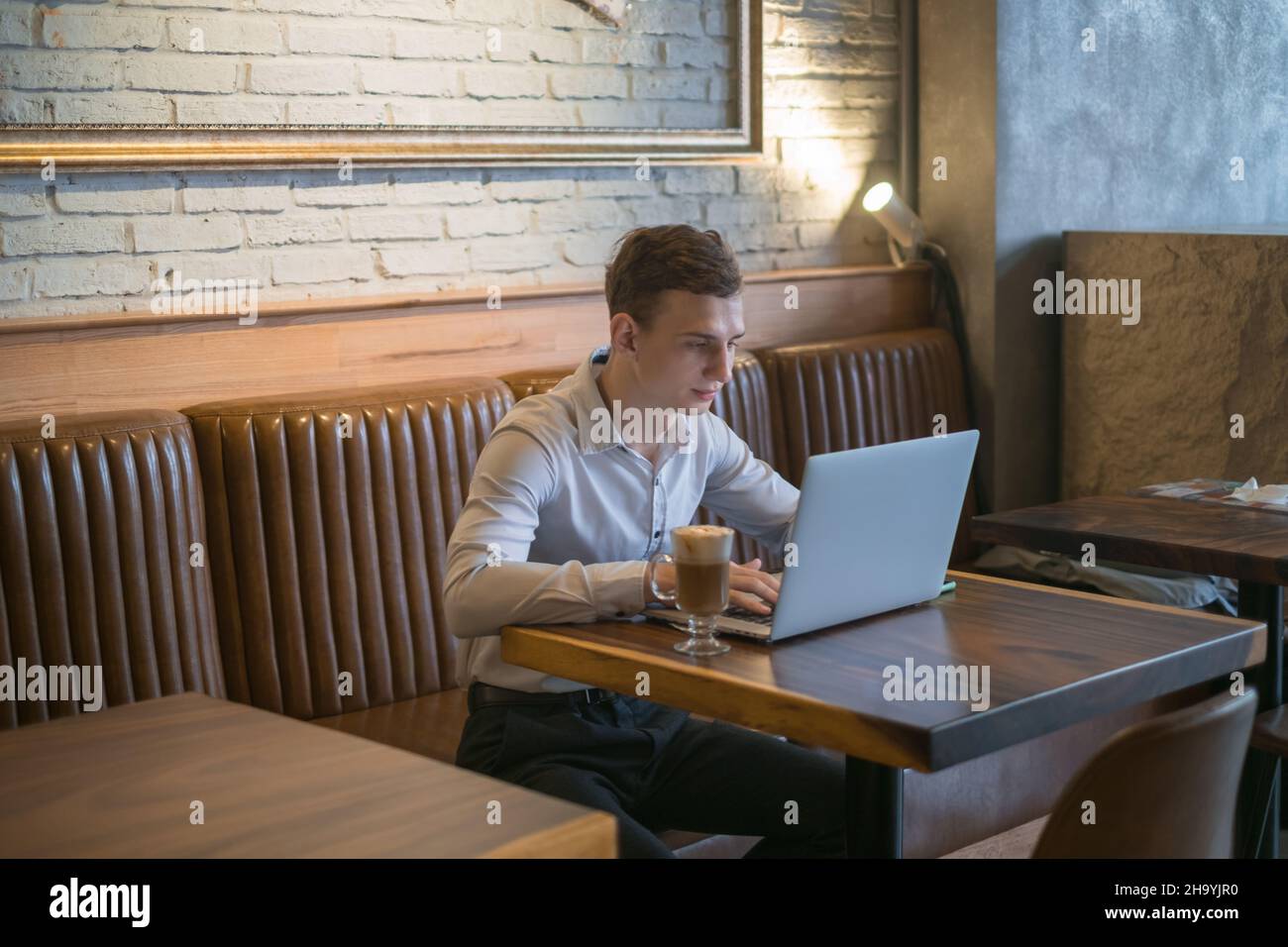 Freelance che lavora in caffetteria con un computer portatile. Pensare, risolvere problemi, nuove idee. Giovane uomo d'affari che naviga in rete su un computer portatile in un bar. Foto Stock