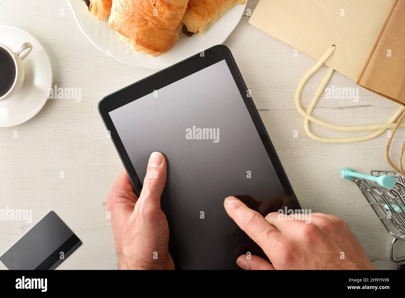 Effettuare un ordine online da casa da un tablet sulla panca della cucina con colazione. Vista dall'alto. Composizione orizzontale. Foto Stock