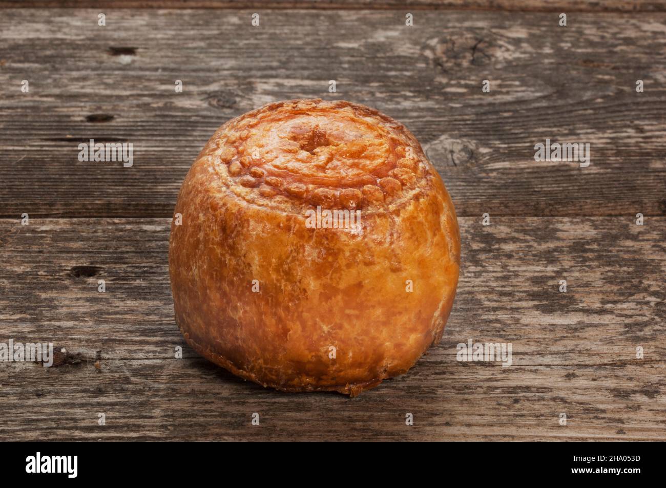 Studio di una piccola torta di maiale poggiata su un pannello di legno scuro - John Gollop Foto Stock