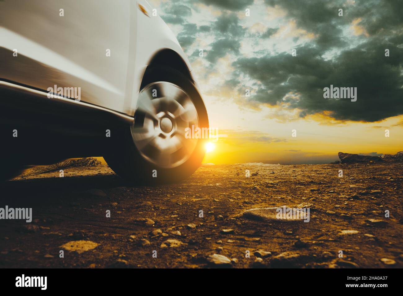 Immagine chiusa di ruote e pneumatici per auto a terra e cielo al tramonto. Viaggio in auto e avventura. Foto Stock