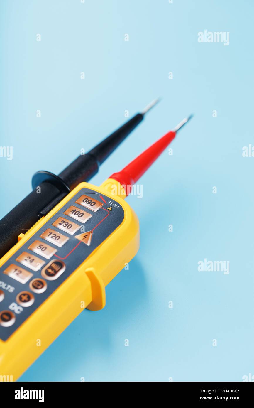 Indicatore di tensione giallo su sfondo blu. Spazio libero Test e verifica delle reti elettriche Foto Stock