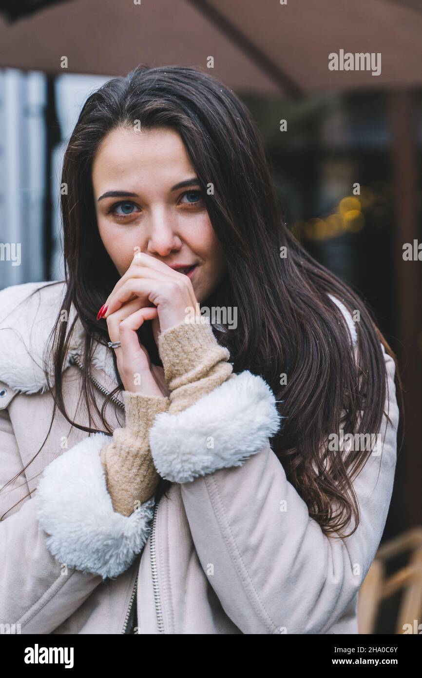 Bella donna sorridente con lunghi capelli indossando una giacca calda passeggiata lungo strada caldo inverno europeo. Protezione dei capelli dal freddo, trattamenti dei capelli. Foto Stock