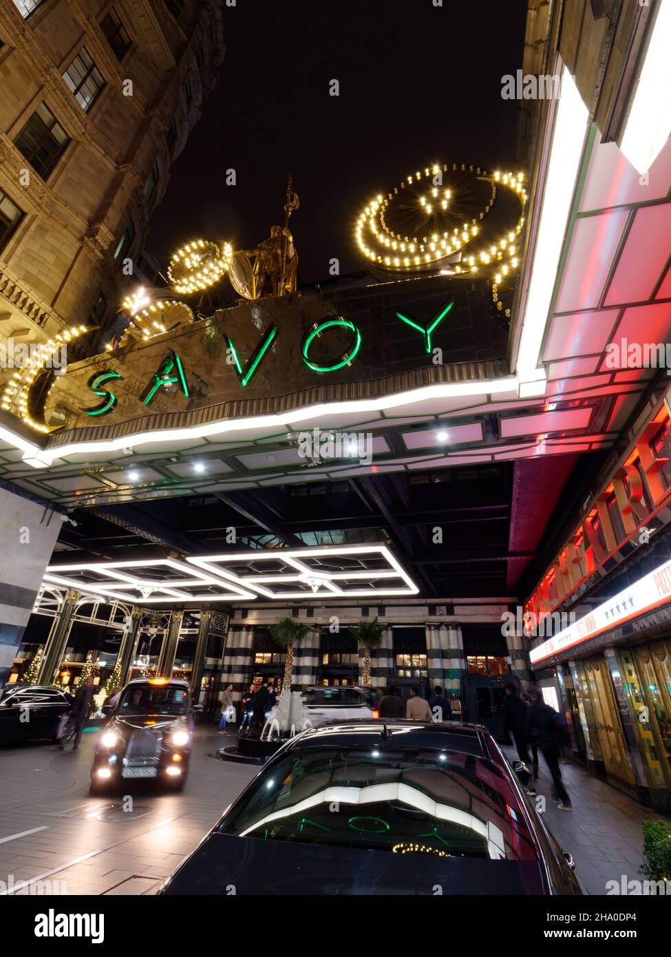 Londra, Greater London, Inghilterra, dicembre 04 2021: L'ingresso dell'hotel di lusso Savoy e taxi in una notte d'inverno a Natale. Foto Stock