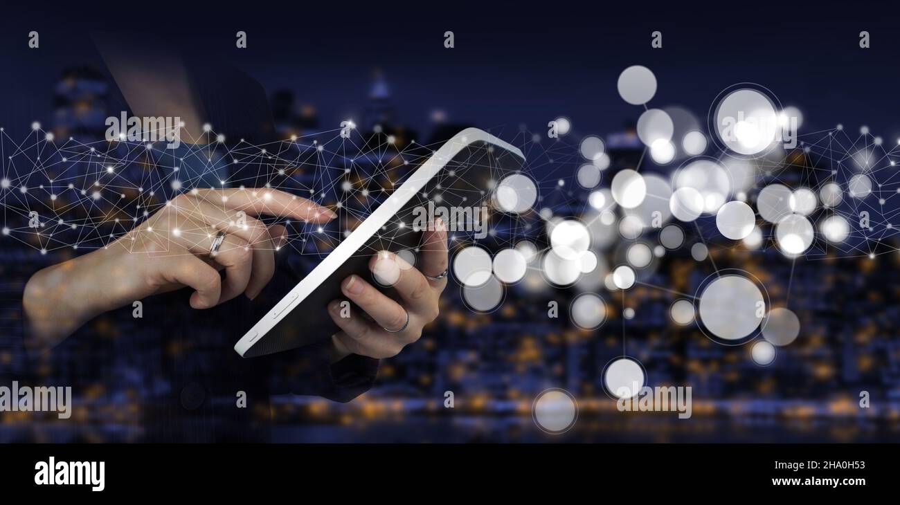 Connessioni di rete innovative e globali, scambi di dati. Tavoletta bianca con ologramma digitale segno circolare sulla città oscura ba sfocata Foto Stock