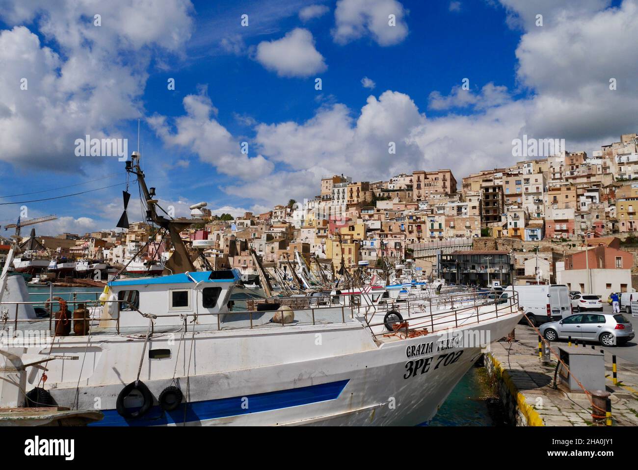 Sciacca, Sicilia, Italia, 24.03.2018. Barche da pesca nel porto con case colorate della città vecchia sullo sfondo. Foto Stock