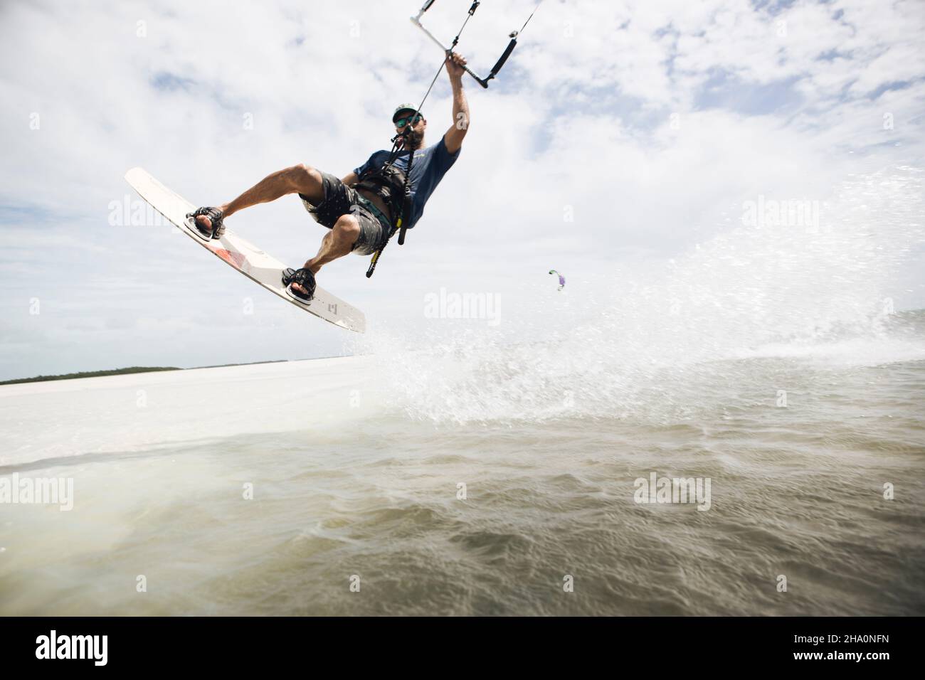 Un uomo kiteboarding nelle chiavi della florida salta fuori dall'acqua Foto Stock