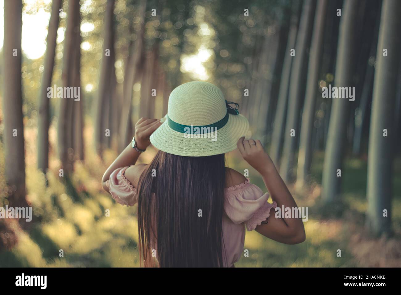 Giovani dai capelli lunghi brunette girl indossando white cappello per il sole e la camicetta rosa all'aperto in un giorno di estate Foto Stock