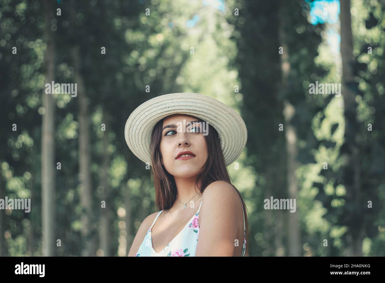 Outdoor ritratto di una giovane attraente brunette donna che indossa bianco sole hat Foto Stock