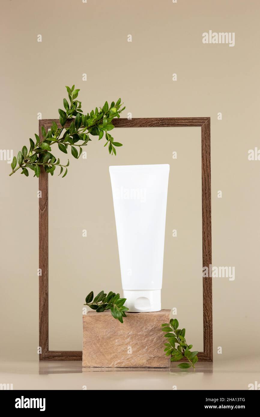 Tubo cosmetico bianco, si erge su una pietra rettangolare beige Foto Stock