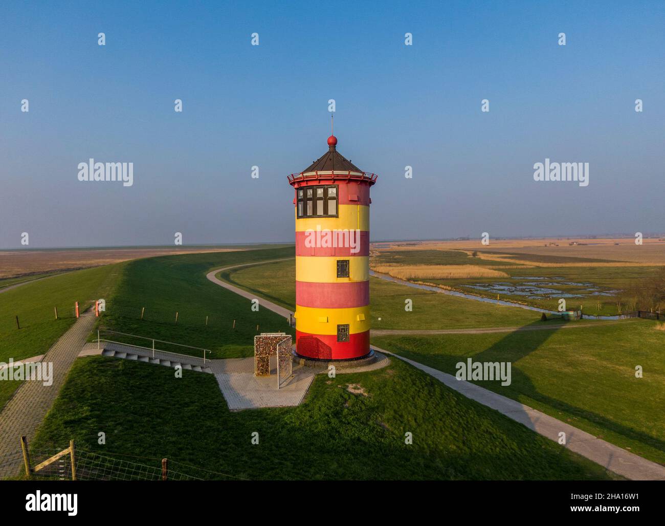 Il faro a righe di colore rosso e giallo Pilsum sulle rive del Mare di Wadden in Germania Foto Stock