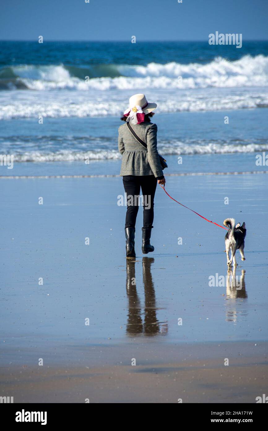 Una donna negli anni '40, di ascendenza messicana, che cammina il suo cane su Tijuana Beach, Tijuana, Messico. Foto Stock