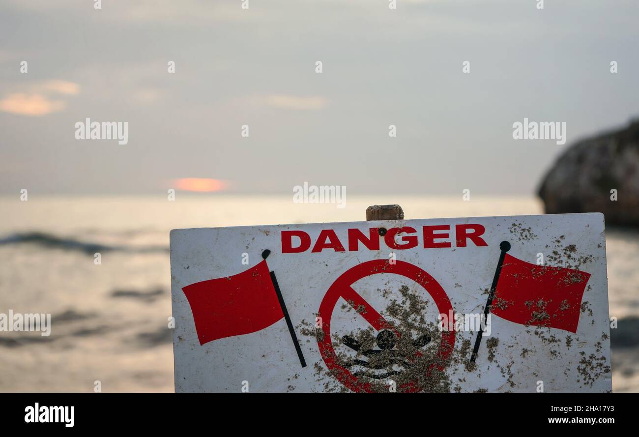 Pericolo non nuotare segno con due bandiere rosse, mare sfocato sullo sfondo Foto Stock