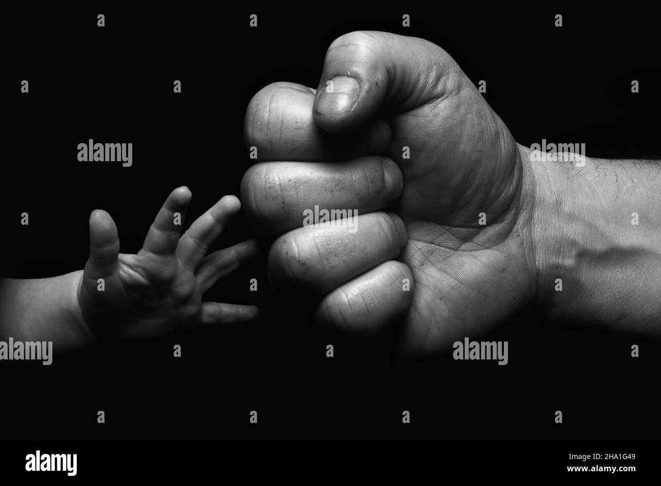 Primo piano in scala di grigi di un uomo cresciuto pugno-bumping mano con una mano di un bambino Foto Stock