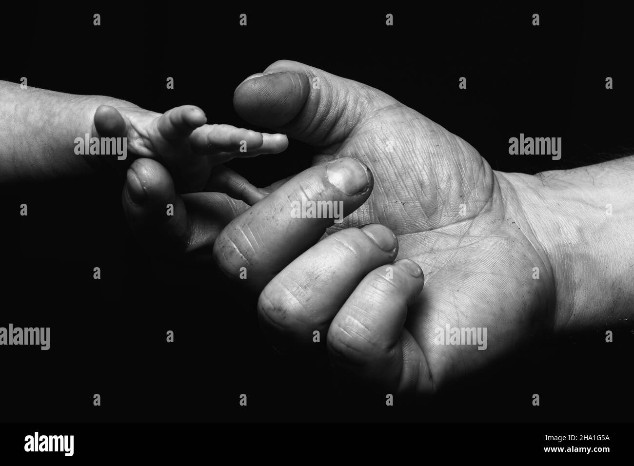 Primo piano in scala di grigi di un uomo cresciuto pugno-bumping mano con una mano di un bambino Foto Stock