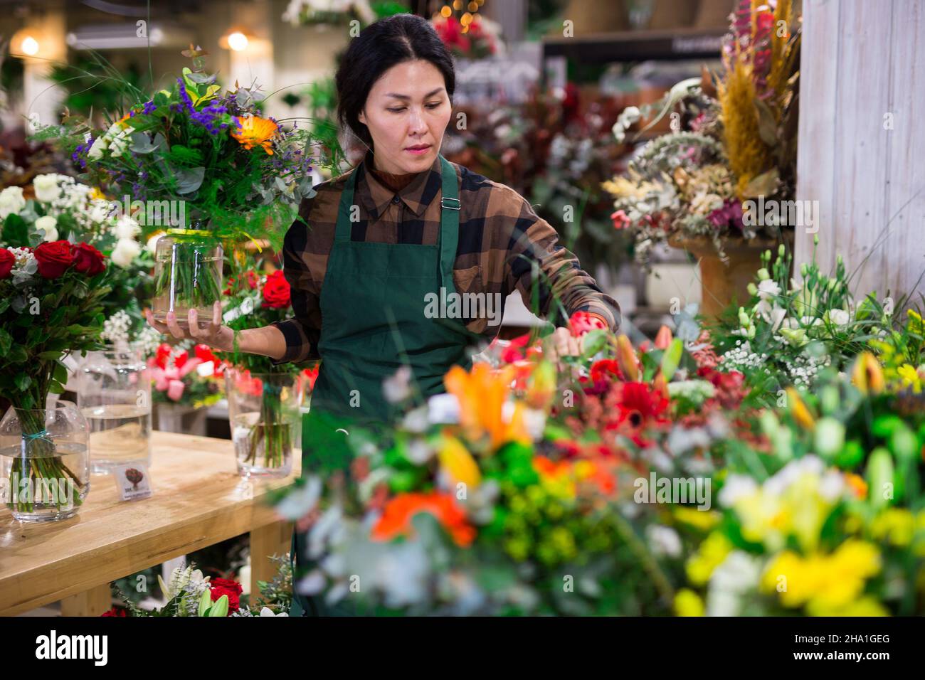 Fiorista femminile asiatico esamina i mazzi in un negozio di fiori Foto Stock