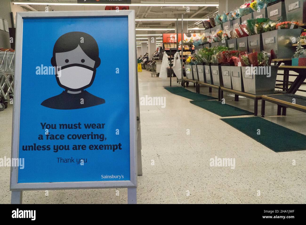 Londra, UK, 6 dicembre 2021: Maschere facciali ora obbligatorie nei negozi a meno che i clienti non siano esenti da cure mediche, nella speranza che possa frenare la diffusione della variante Omicron del coronavirus, che si ritiene sia già in trasmissione comunitaria. In questo ramo di Sainsbury's un segno prominente all'ingresso chiede ai clienti di cooperare per mantenere gli altri al sicuro. Anna Watson/Alamy Live News Foto Stock