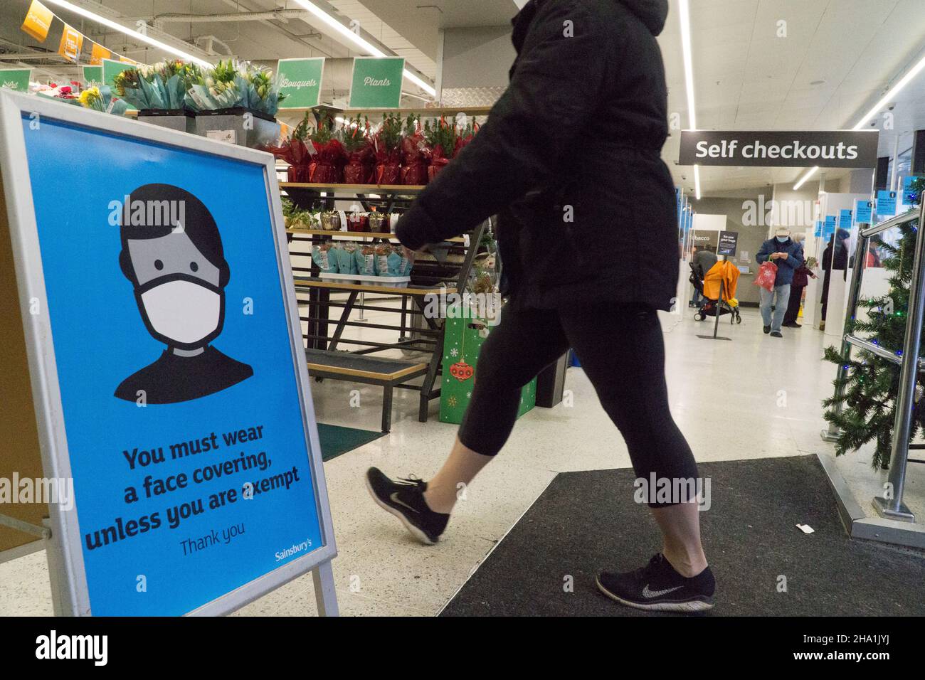 Londra, UK, 6 dicembre 2021: Maschere facciali ora obbligatorie nei negozi a meno che i clienti non siano esenti da cure mediche, nella speranza che possa frenare la diffusione della variante Omicron del coronavirus, che si ritiene sia già in trasmissione comunitaria. In questo ramo di Sainsbury's un segno prominente all'ingresso chiede ai clienti di cooperare per mantenere gli altri al sicuro. Anna Watson/Alamy Live News Foto Stock