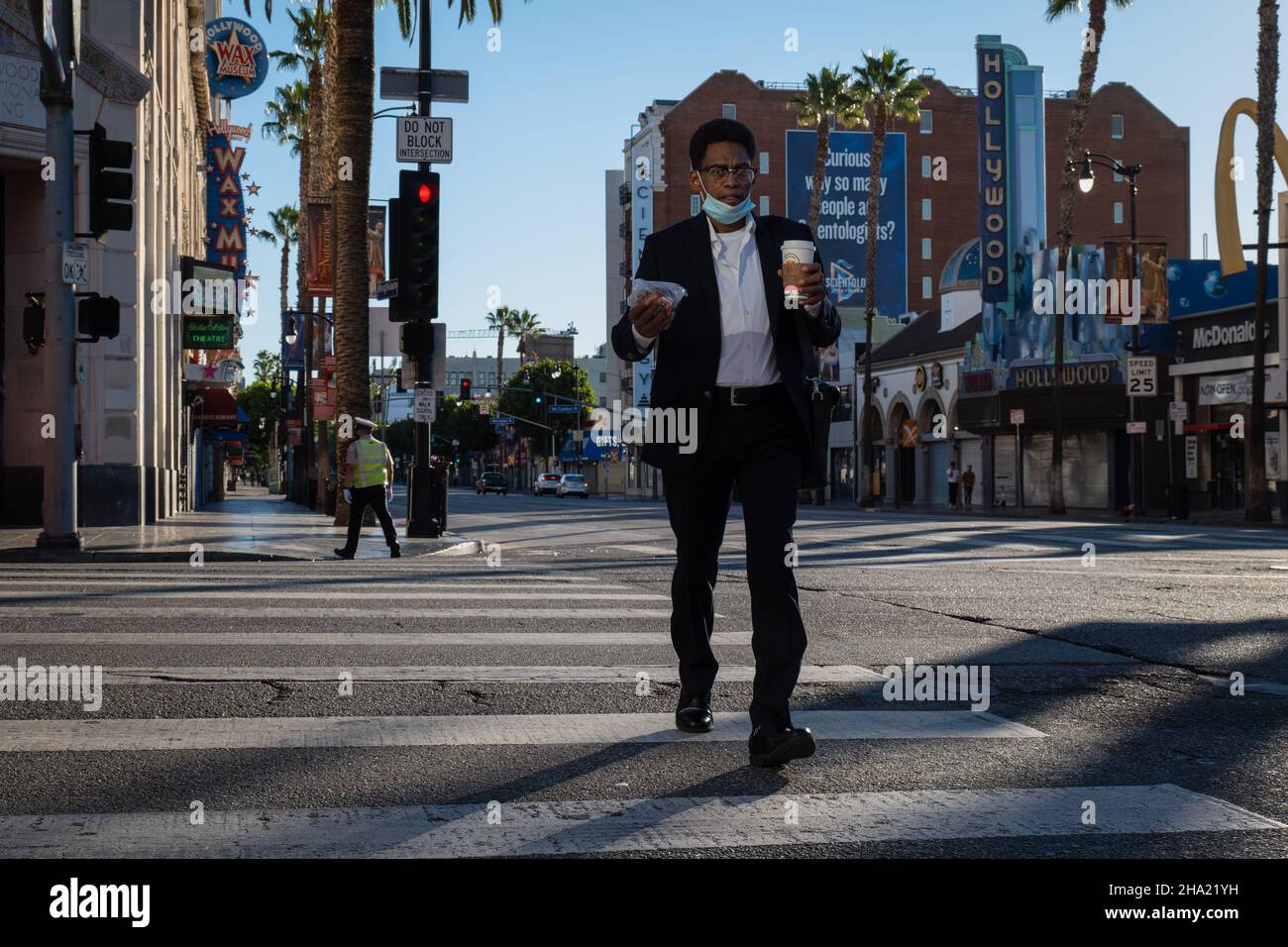 Man attraversa l'incrocio tra Highland e Hollywood Blvd a Hollywood, CALIFORNIA Foto Stock