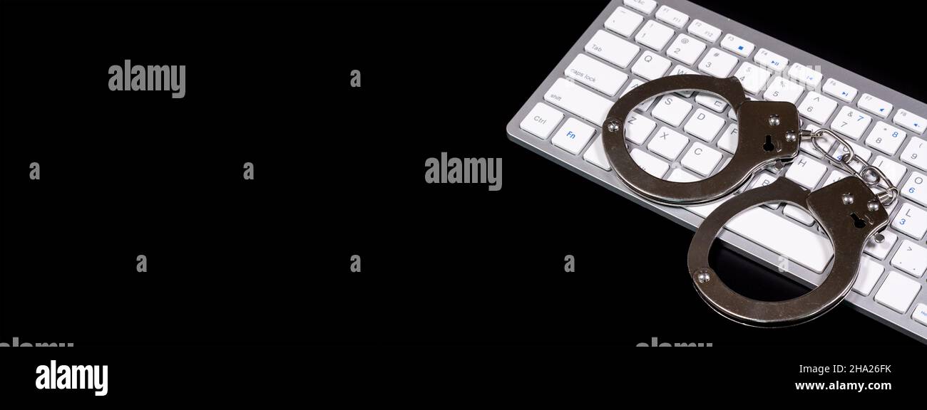 Tastiera e manette con le spie LED accese. Concetto di cibercriminalità Foto Stock