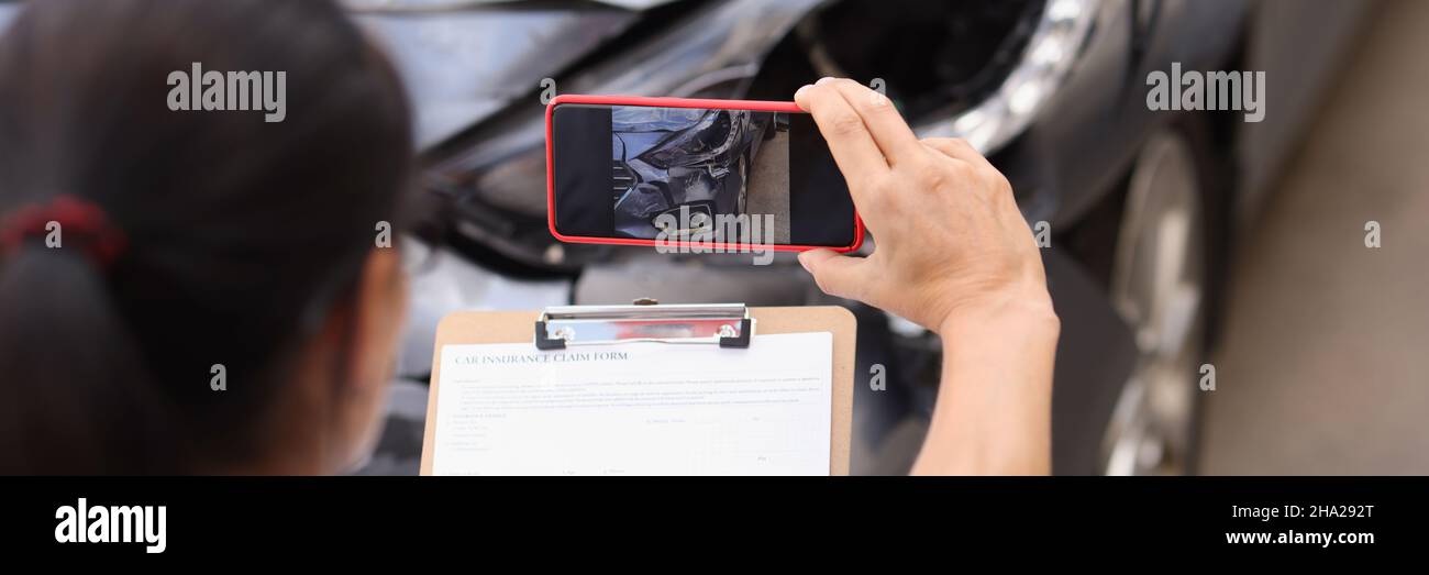 L'agente assicurativo sta riprendendo i danni all'auto che si è schiantata Foto Stock