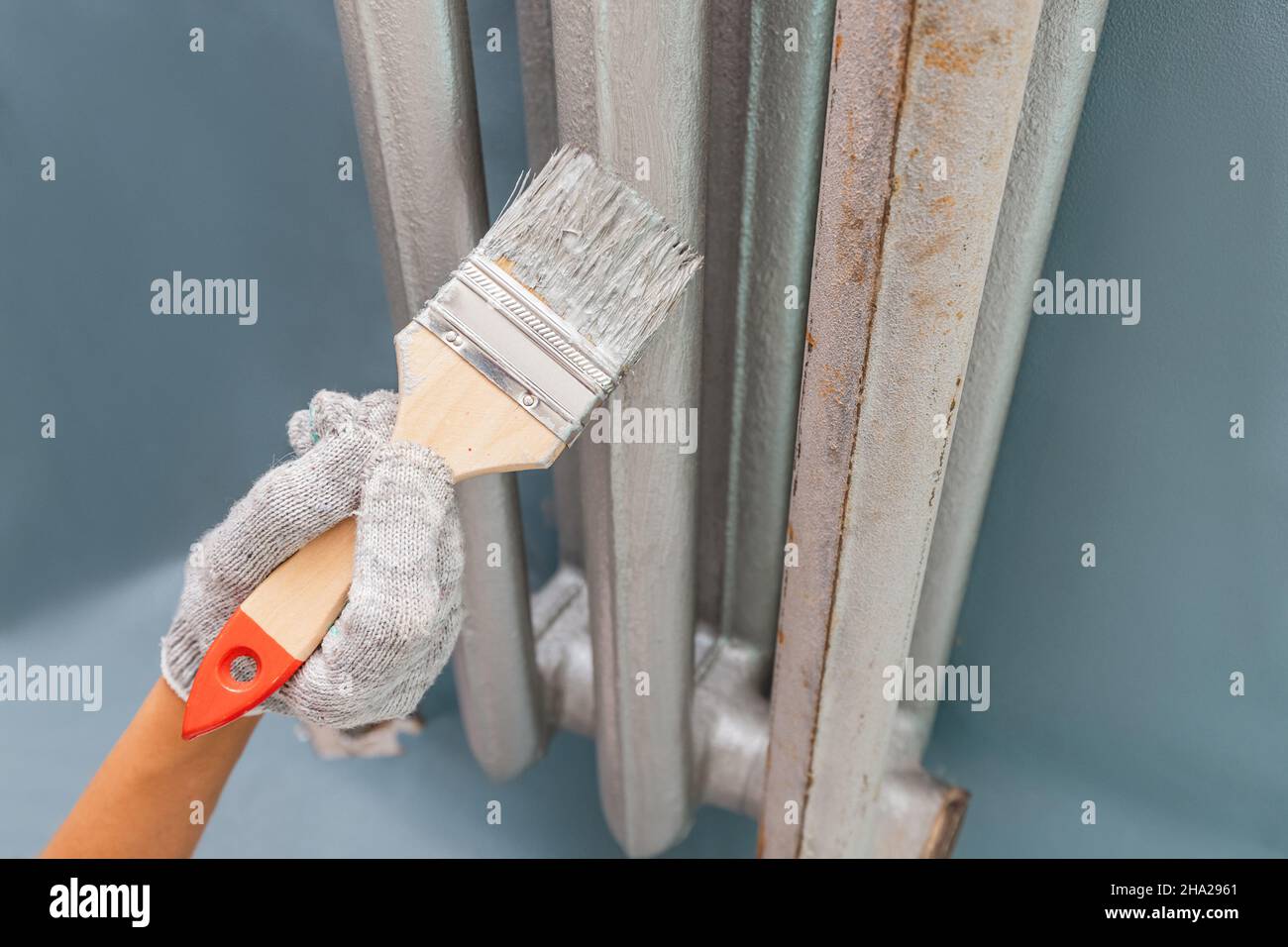 verniciatura del radiatore di riscaldamento nell'appartamento con una speciale vernice argentata termoresistente Foto Stock
