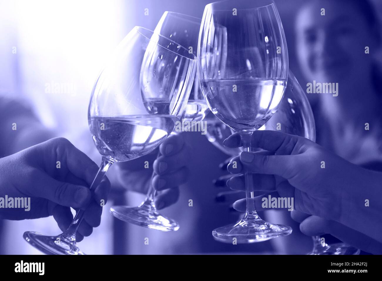 Gruppo di amici che godono di drink serali. Primo piano di pane tostato con vino bianco. Colore di 2022 anni, molto peri Foto Stock