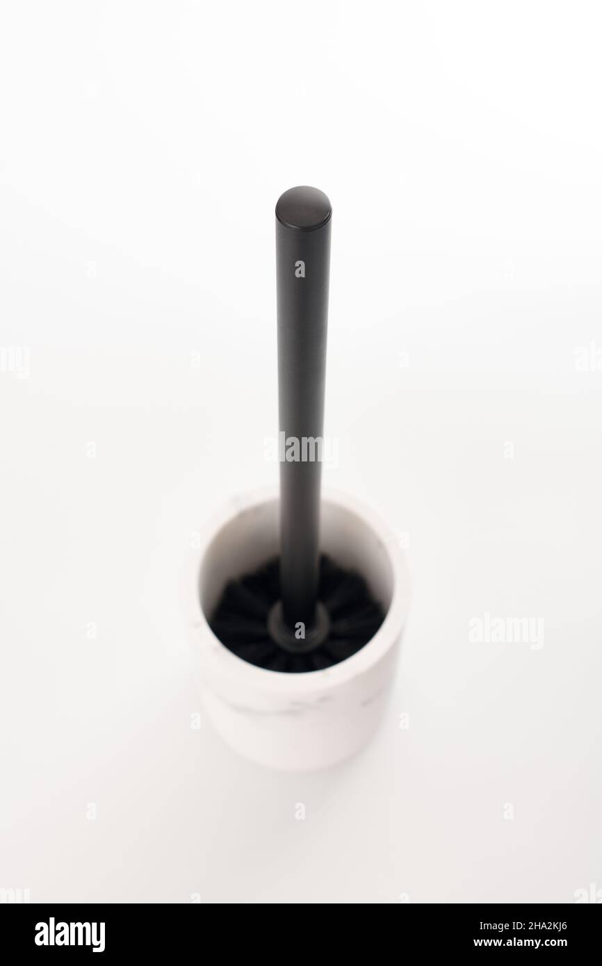 Spazzola igienica nera in moderno supporto in pietra bianca isolato sfondo bianco. WC per la pulizia della tazza del water. Spazzola per detergente per toletta e candeggina Foto Stock