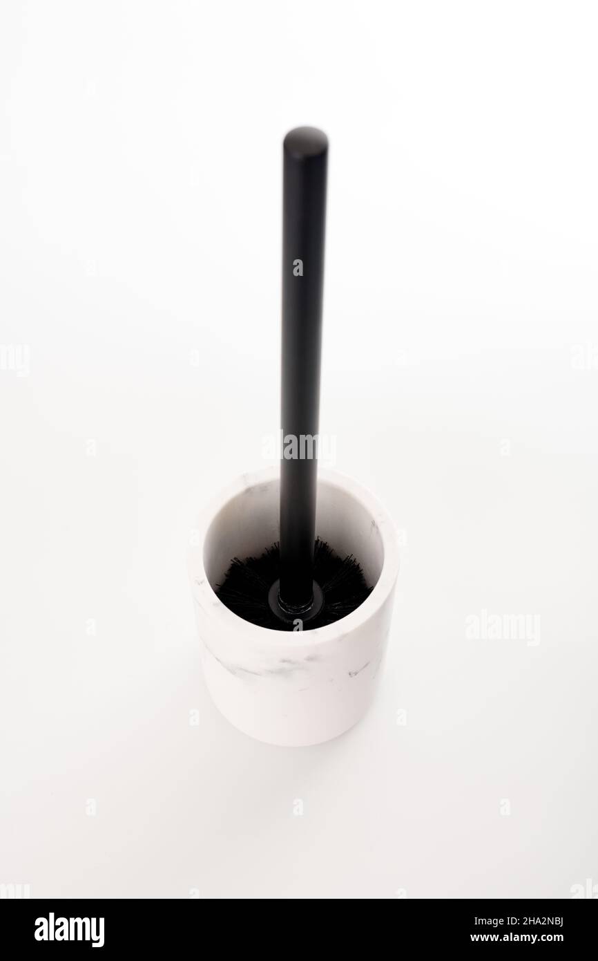 Spazzola igienica nera in moderno supporto in pietra bianca isolato sfondo bianco. WC per la pulizia della tazza del water. Spazzola per detergente per toletta e candeggina Foto Stock