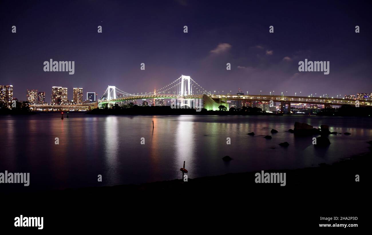 Rainbow Bridge di notte di fronte allo skyline di Tokyo Foto Stock