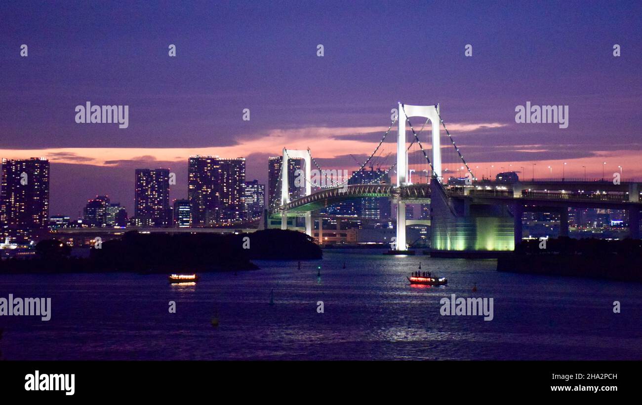 Rainbow Bridge di notte di fronte allo skyline di Tokyo Foto Stock