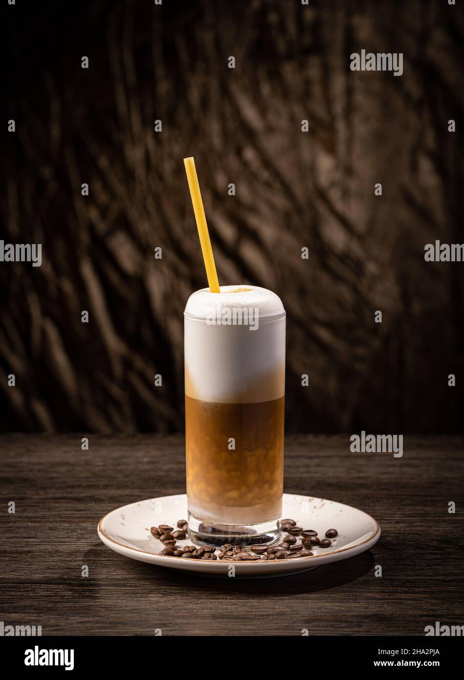 Tazza di caffè in un bicchiere lungo e trasparente. Latte con ghiaccio e paglia Foto Stock