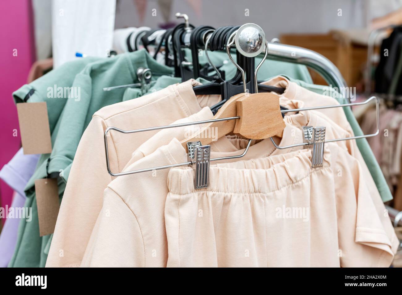 Abiti casual alla moda in colori pastello su un appendiabiti nel negozio Foto Stock