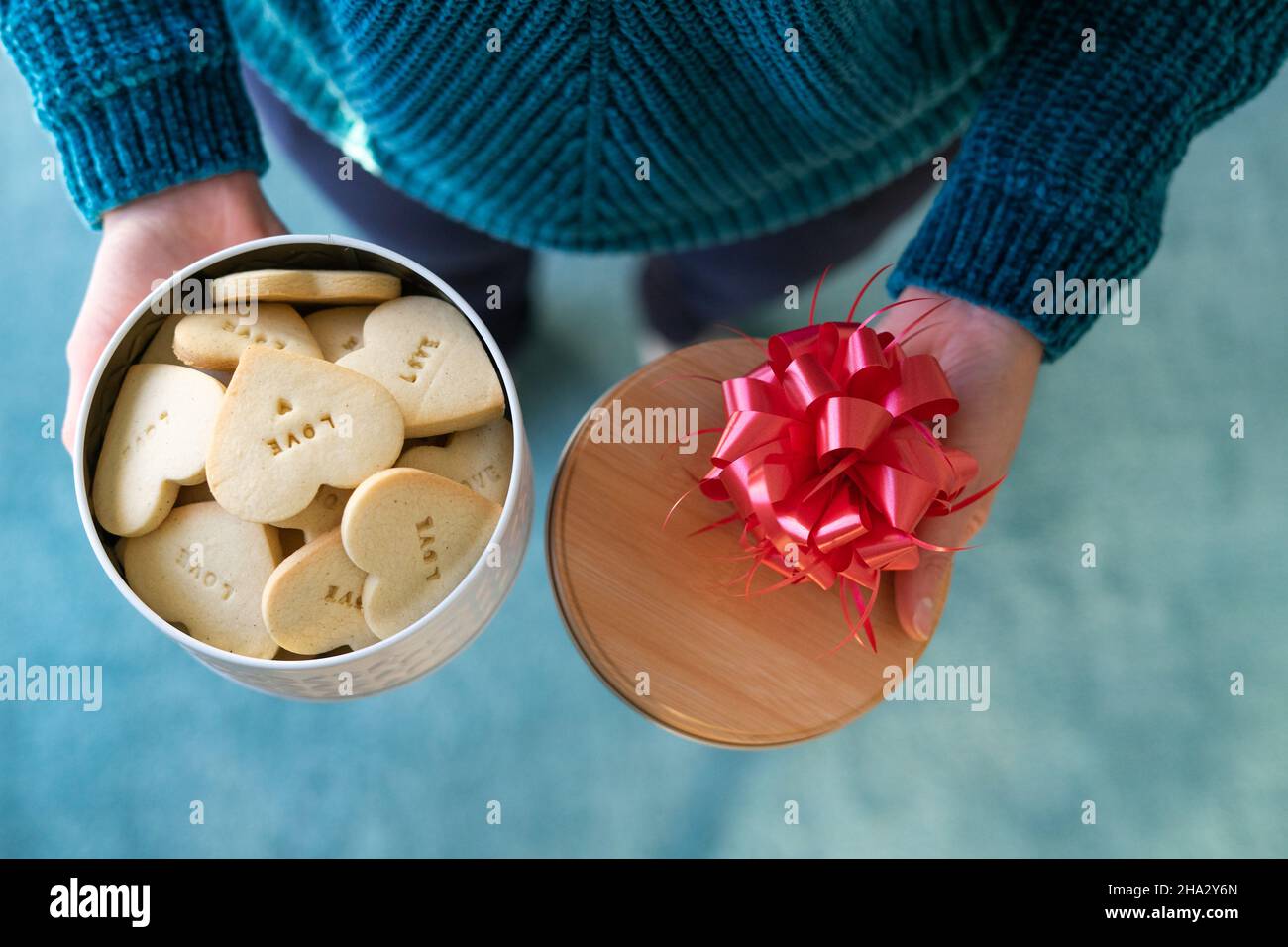 Aprire una scatola di biscotti a forma di cuore. Le mani della donna. San Valentino. Spazio di copia Foto Stock