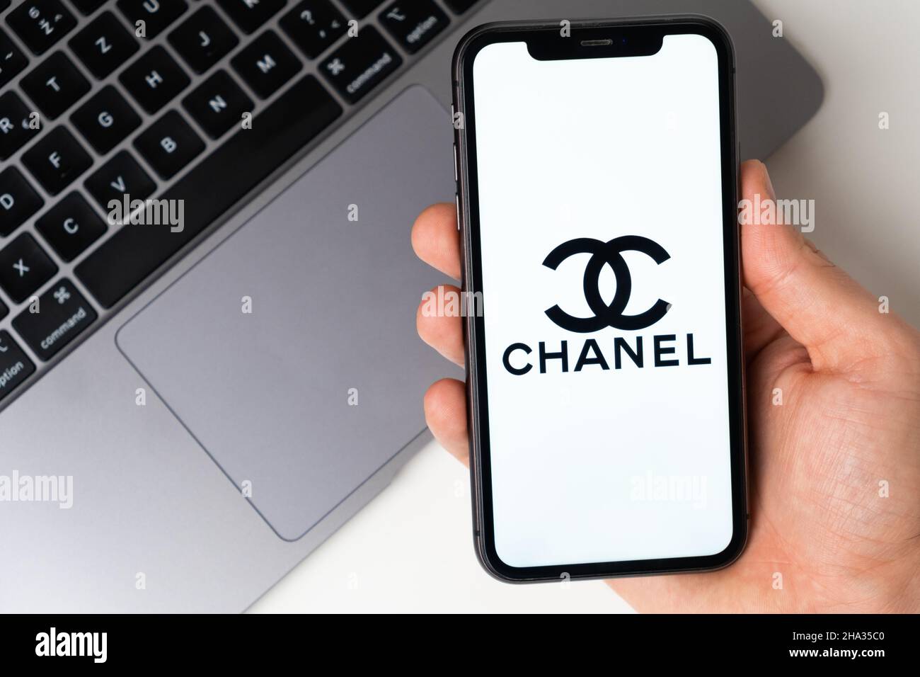 Chanel applicazione mobile sullo schermo dello smartphone. Fai acquisti mentre sei seduto a casa utilizzando un'app mobile o un notebook. Uno smartphone in una mano di un uomo. Novembre 2021, San Francisco, USA Foto Stock