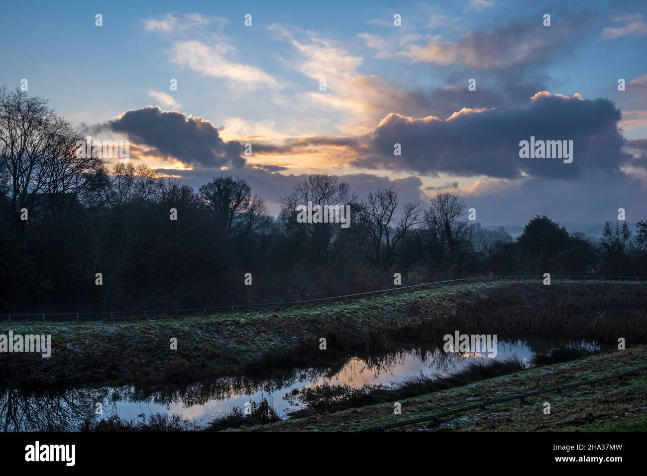 Tramonto su un laghetto di gestione delle acque piovane accanto ad un nuovo sviluppo abitativo, Oaklands Park, Ashbourne, Derbyshire Foto Stock