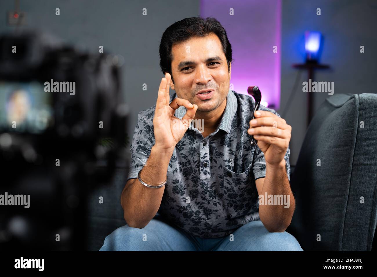 Giovane influencer indiano che spiega il rullo di derma ed il relativo uso registrando sulla macchina fotografica a casa - concetto di cura della pelle e suggerimenti di equità da Foto Stock