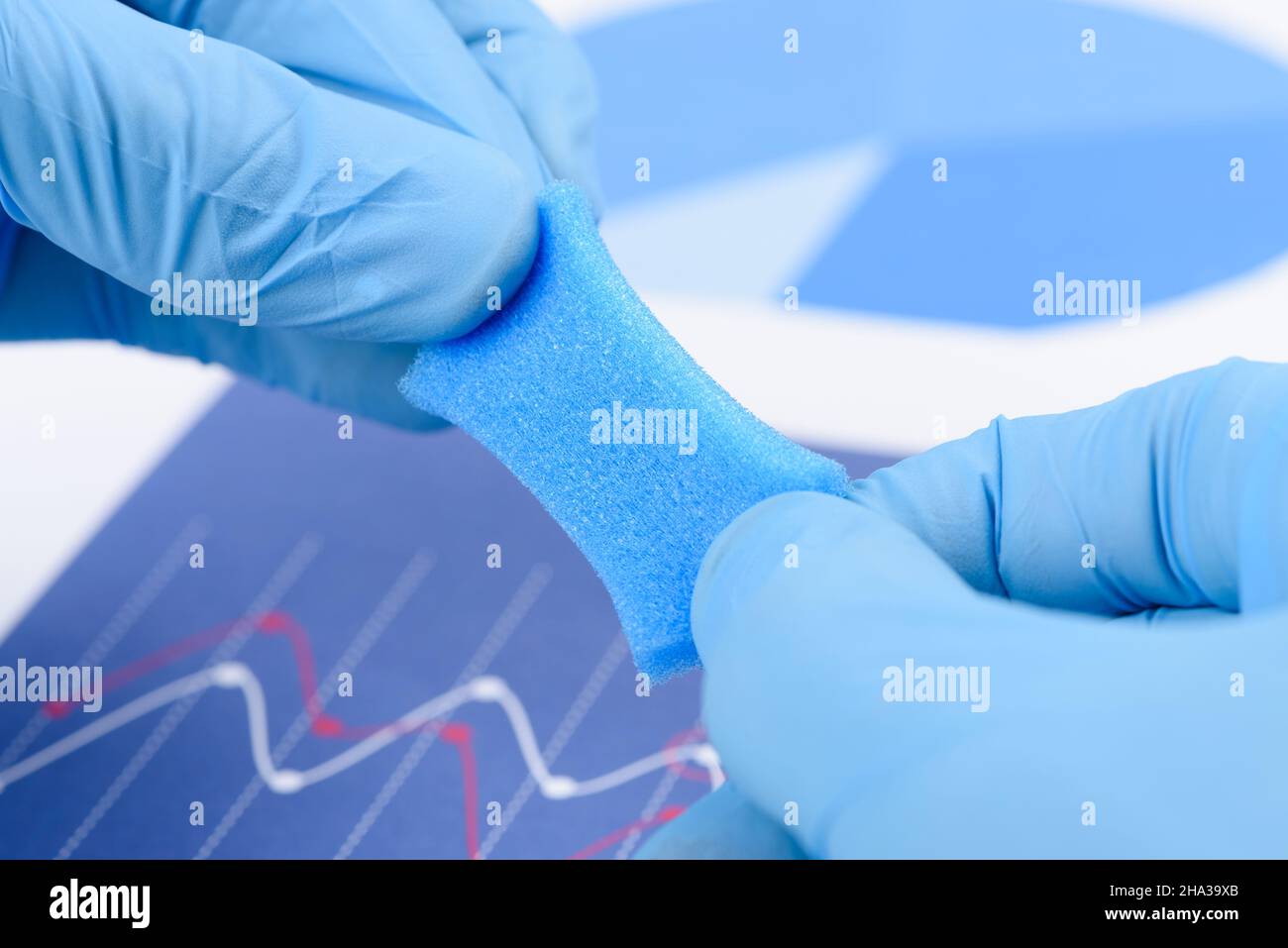 Materiale simile a schiuma porosa blu stirato nelle mani dello scienziato in laboratorio. Ricerca di materiale con nuovo concetto di proprietà. Foto Stock