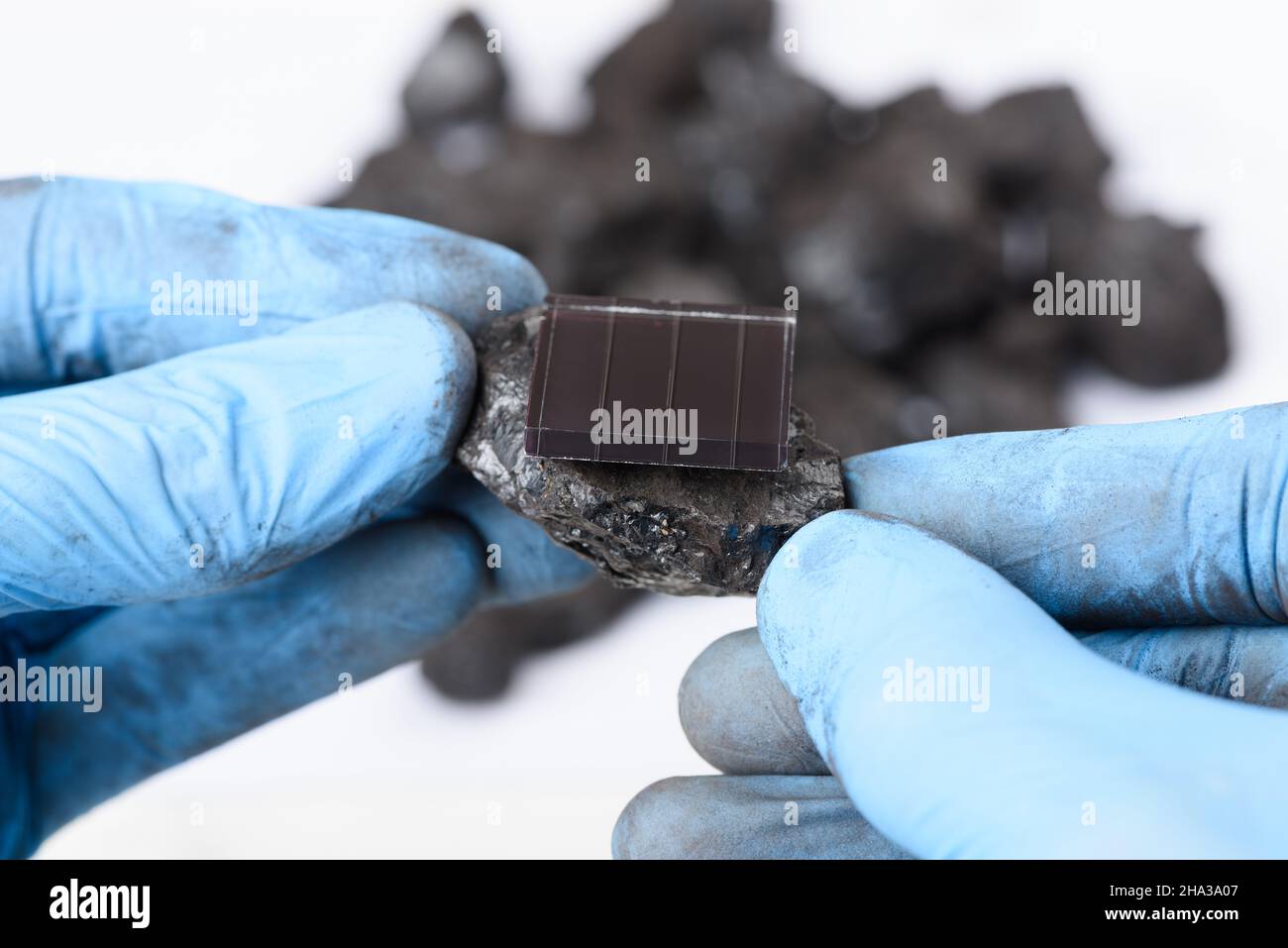 Pannello solare su grumo di carbone nelle mani dello scienziato. Transizione dei combustibili fossili al concetto di ricerca sulle energie rinnovabili. Foto Stock