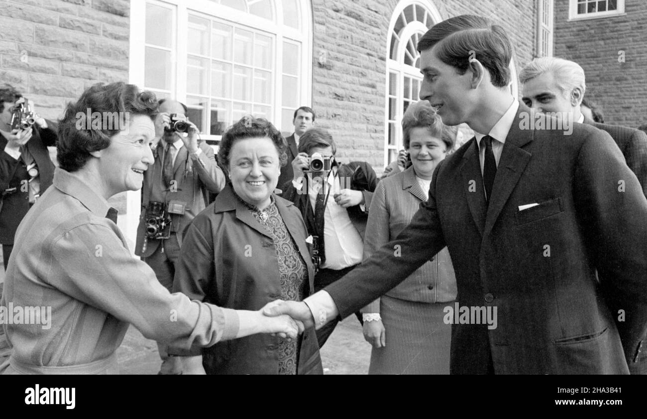 Foto del file datata 20/4/1969 di Miss E. Davies (a sinistra), supervisore della mensa dell'Università del Galles, Aberystwyth, scuotendo le mani con il Principe Carlo al suo arrivo alla Pantycelyn Hall of Residence al college. Il Principe è tornato ad aprire la nuova Scuola di Scienze veterinarie della Aberystwyth University. Data di emissione: Venerdì 10 dicembre 2021. Foto Stock