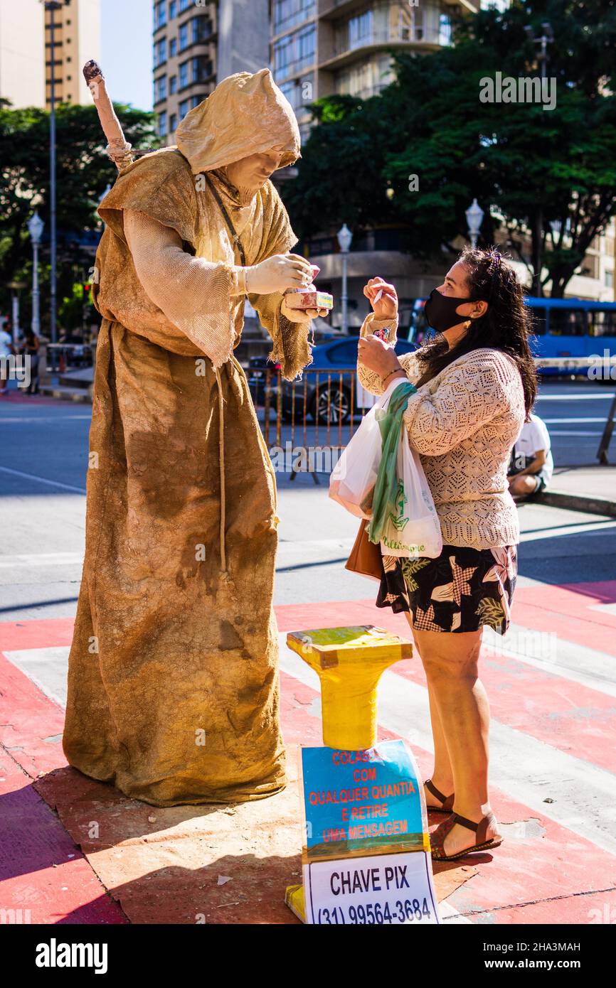 Donna che interagisce con una statua dal vivo, artista di strada coperto di fango secco al fango presso la Fiera di Belo Horizonte Hippie a Belo Horizonte, Minas Gerais, Foto Stock