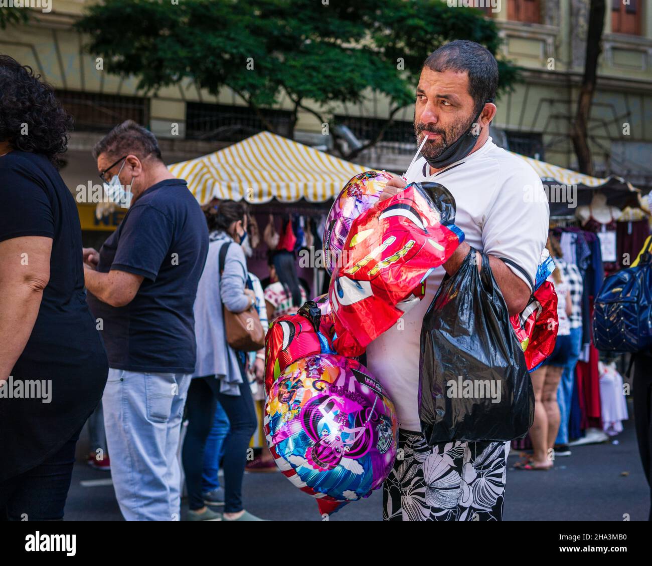Il venditore di palloncini maschio gonfia un palloncino con la bocca alla fiera di Belo Horizonte Hippie, a Belo Horizonte, Minas Gerais, Brasile. Foto Stock