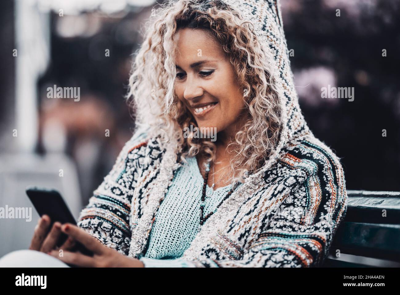 ritratto di giovane adulto bella donna sorridere e utilizzare il telefono cellulare all'aperto al parco seduto sulla panca. le donne utilizzano la connessione cellulare. moderno stile di vita applicazione tecnologia smatphone Foto Stock