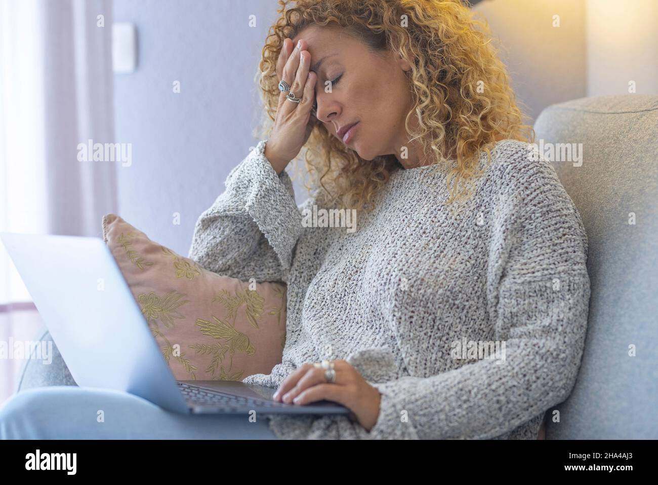 triste stanca giovane donna toccare fronte avendo emicrania emicrania o depressione, adulta frustrato che lavora sul computer portatile seduto sul divano a casa Foto Stock