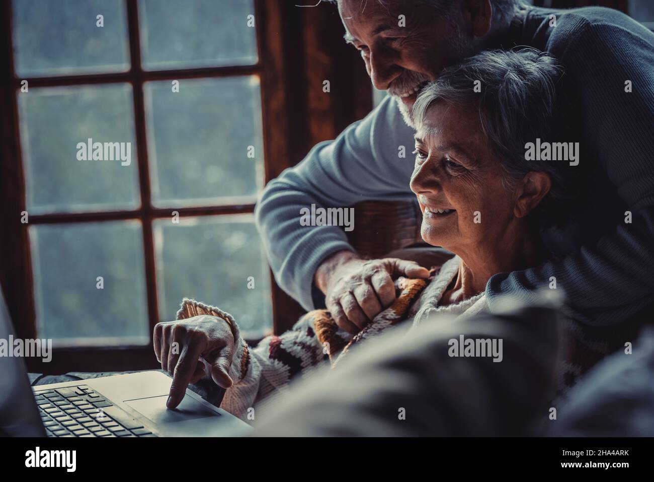 la coppia anziana usa il computer portatile a casa di notte insieme sorridendo e godendo della connessione internet online. felice pensionato persone uomo e donna navigare sul web e divertirsi con la tecnologia di rete internet Foto Stock
