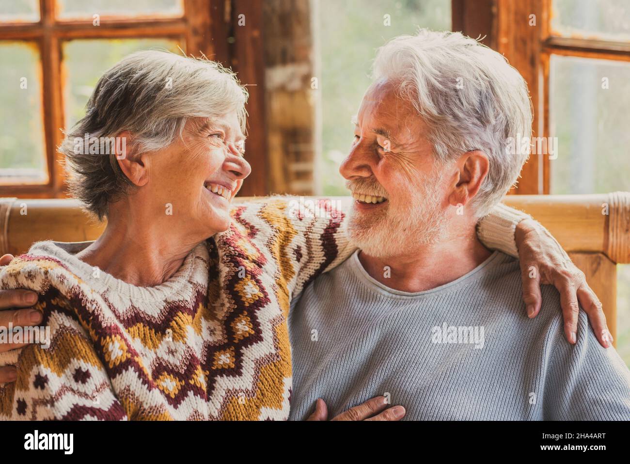 coppie anziane stile di vita felice con uomo e donna che si guardano l'un l'altro con amore e amicizia seduti a casa. persone allegre età anziana godere della vita e attività indoor tempo libero Foto Stock