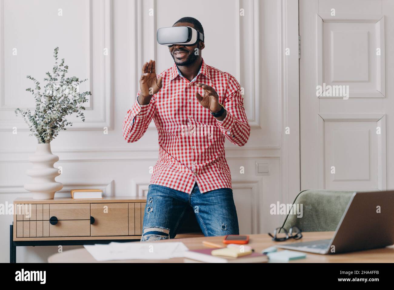 L'uomo africano in visore VR interagisce con l'interfaccia digitale, utilizzando un dispositivo innovativo per le aziende Foto Stock