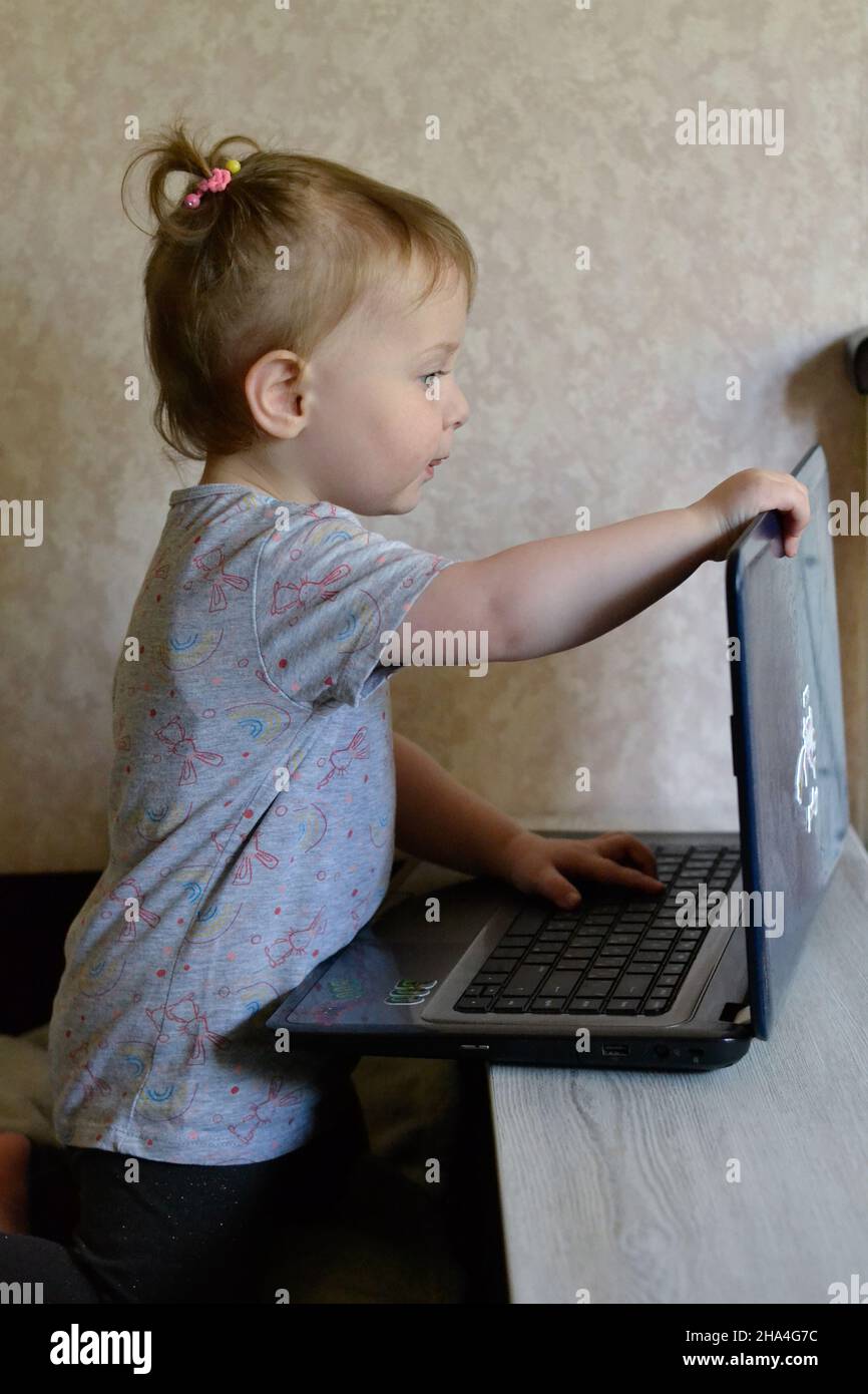 bambina che usa il computer portatile mentre si siede sul letto Foto Stock