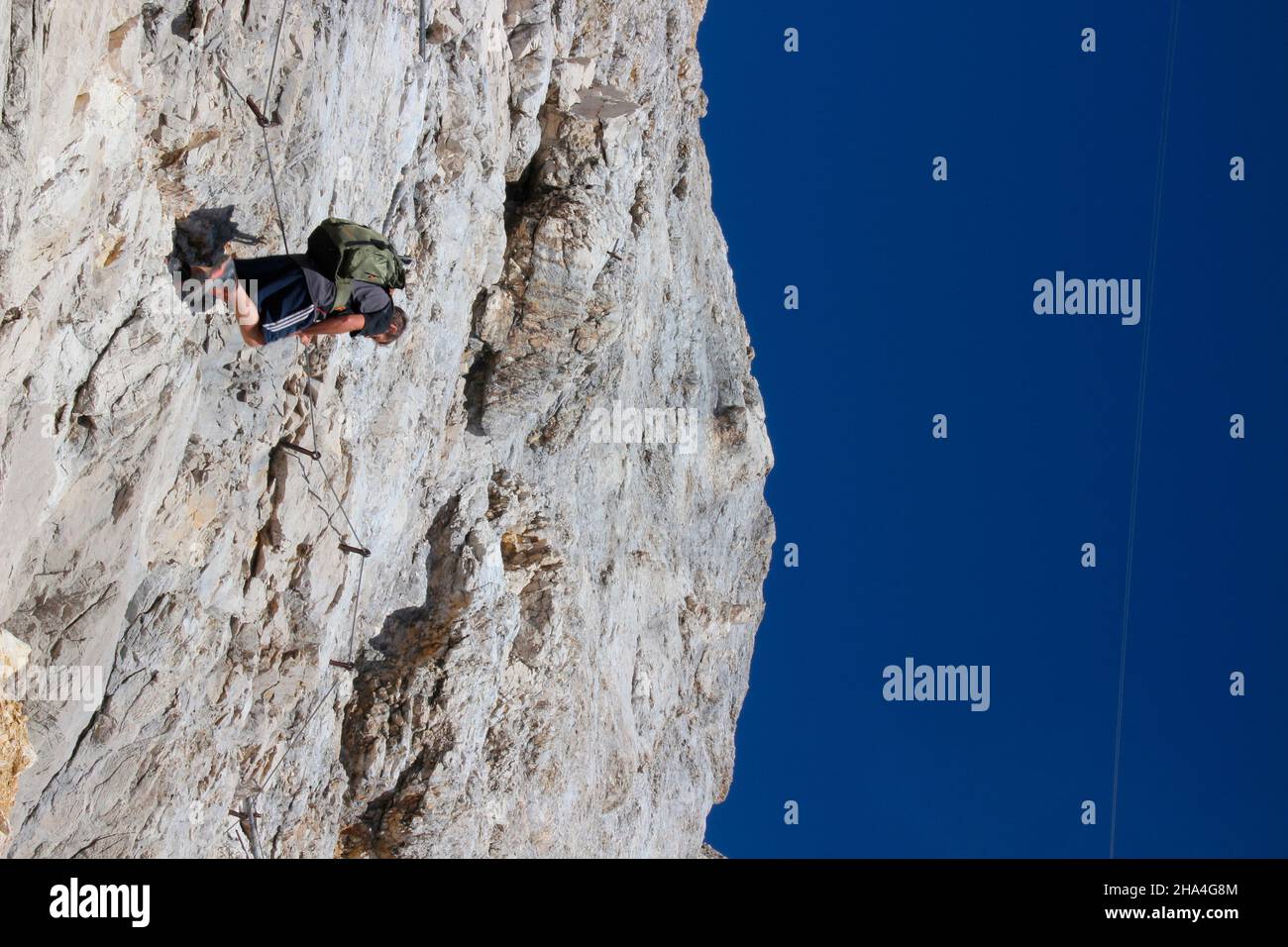 uomo di mezza età sulla via ferrata a zugspitze, vista dal basso, wetterstein montagne blu cielo, zaino, garmisch-partenkirchen, loisachtal, alta baviera, baviera, germania meridionale, germania, europa, Foto Stock